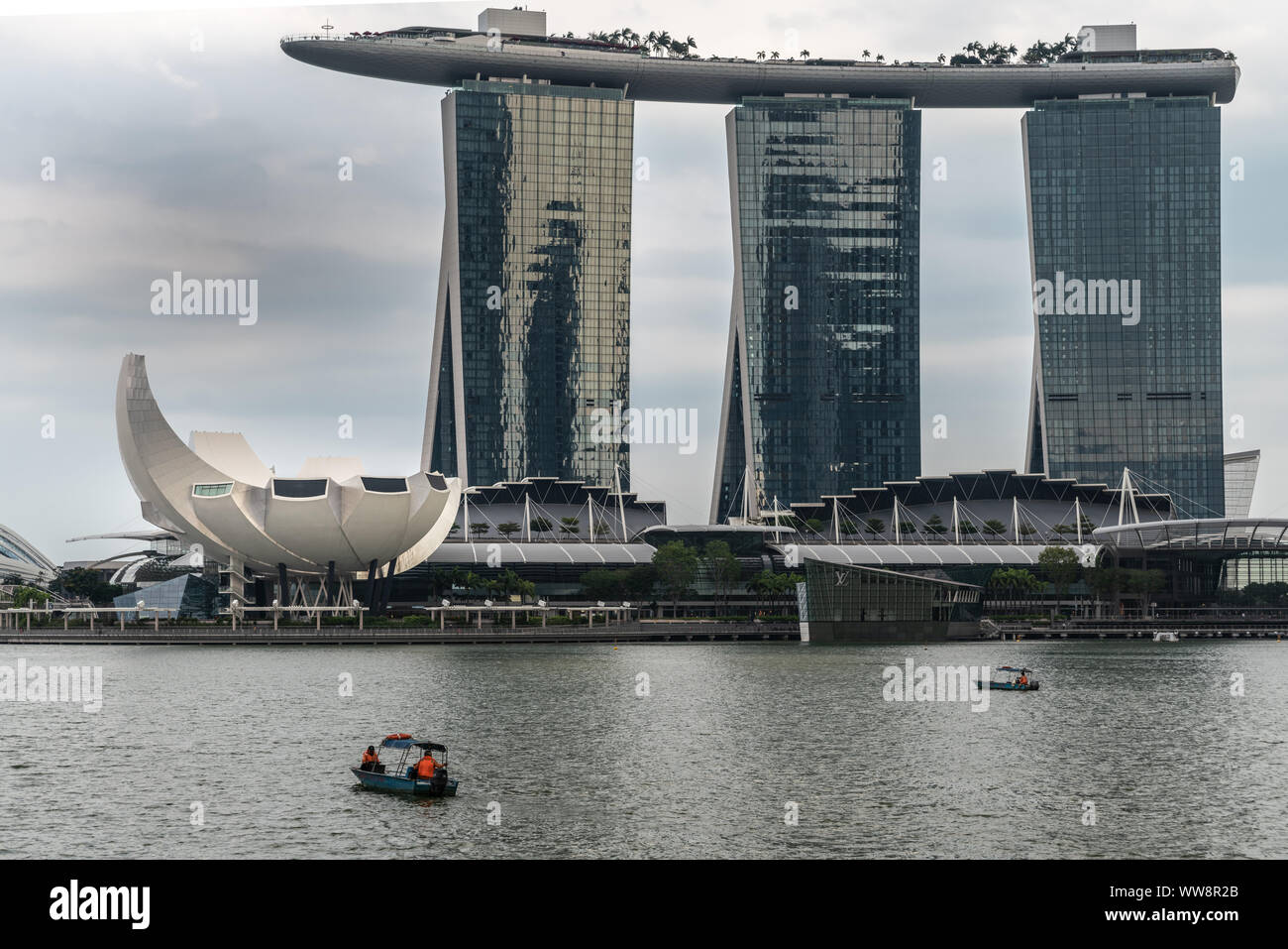 Singapur - März 20, 2019: Marina Bay Sands Hotel und Casino mit seinen drei Türmen von hinter der Bucht unter regnerischen Schwere cloudscape gesehen. Weißes Oberteil ist Stockfoto