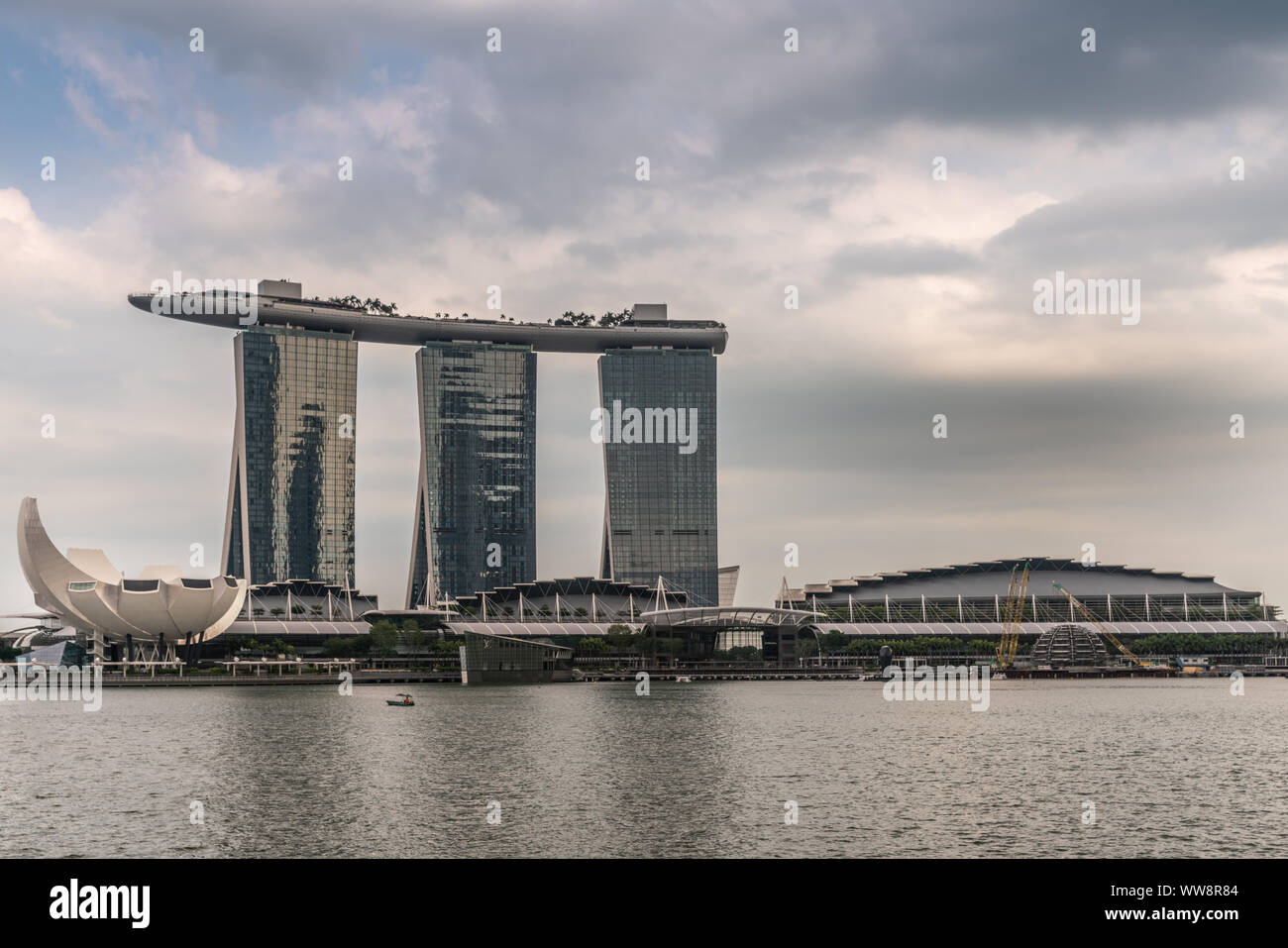 Singapur - März 20, 2019: Marina Bay Sands Hotel und Casino mit seinen drei Türmen von hinter der Bucht unter schweren cloudscape mit blauen Flecken gesehen. Weiß Stockfoto