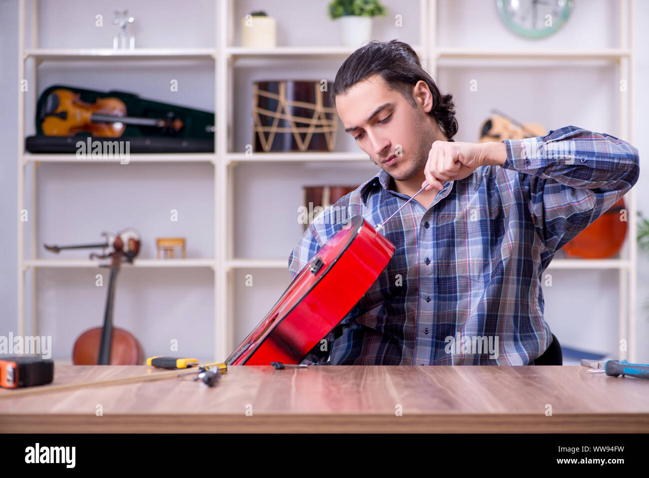Die junge schöne Handwerker Reparatur Gitarre Stockfoto