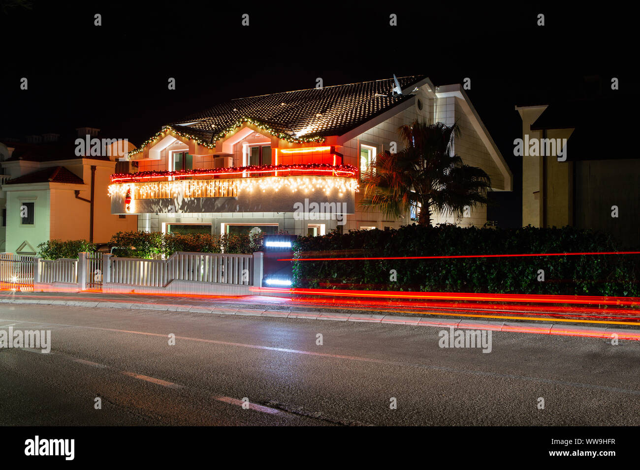 Haus mit Weihnachtsbeleuchtung. An der Straße Auto, Spuren zu hinterlassen. Lange Belichtung. Stockfoto