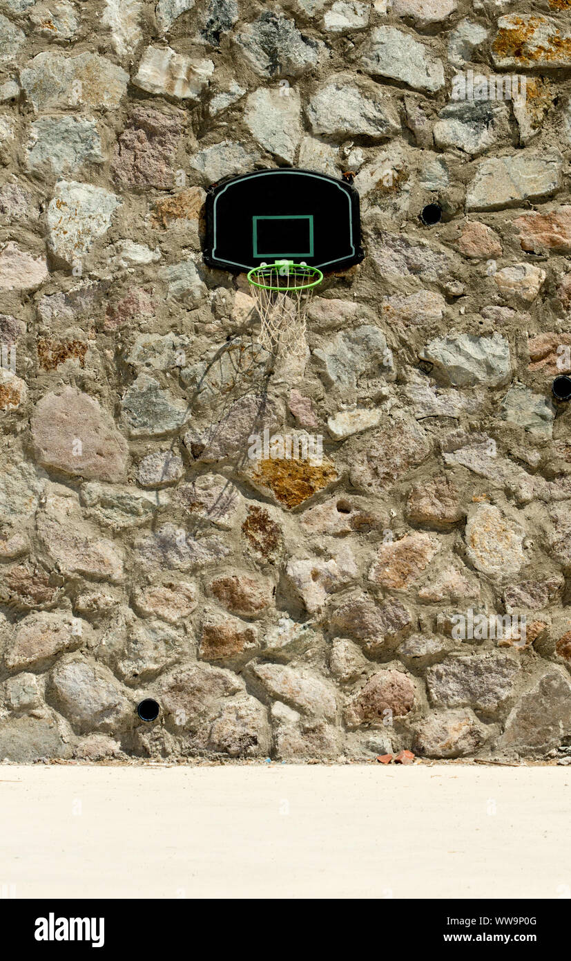 Ein Basketballbackboard mit grünem Rand an einer Wand aus Steinmauerwerk mit großem Kopierraum. Verteidigung im Sportspielkonzept. Stockfoto