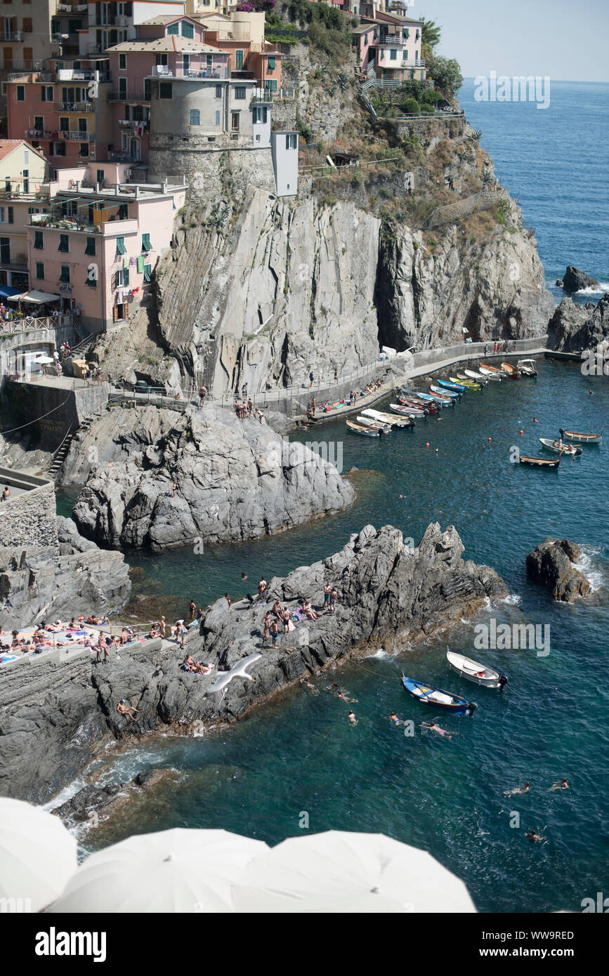 Manarola, Italien - Juli 2, 2018: An einem heißen Sommer Tag, Badegäste sammeln entlang der felsigen Meer in Manarola, einer der fünf traditionellen Cinque Terre Fisch Stockfoto