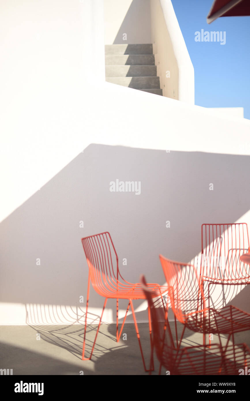 Santorini, Griechenland - 23. Juni 2018: am frühen Morgen Licht auf rote Metall Stühle und eine weiß-graue Treppe in Santorini. Stockfoto