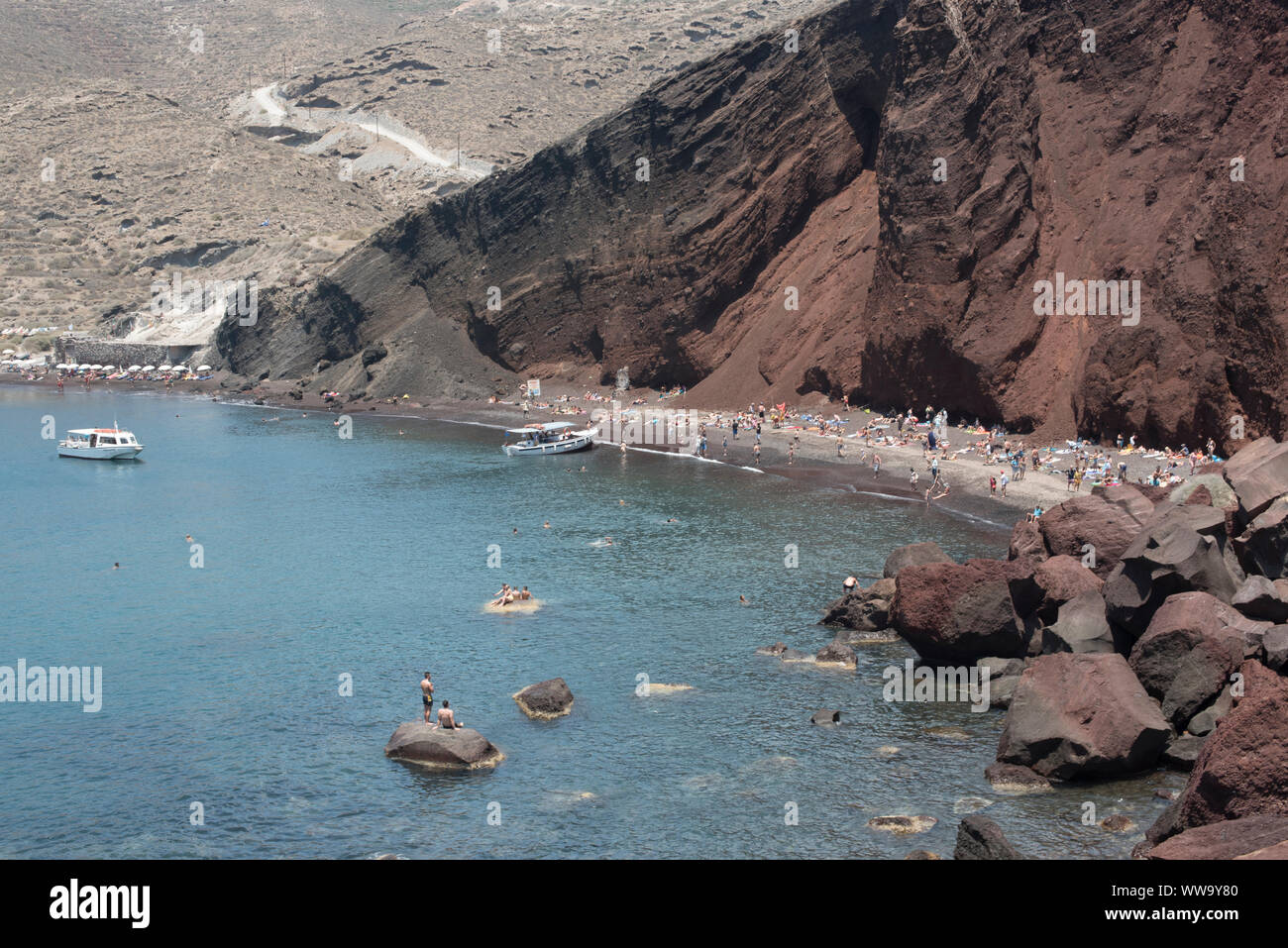 Santorini, Griechenland - 24. Juni 2018: Menschenmassen und Boote auf Roten Strand, ein beliebtes Reiseziel an der Südküste von Santorin. Stockfoto