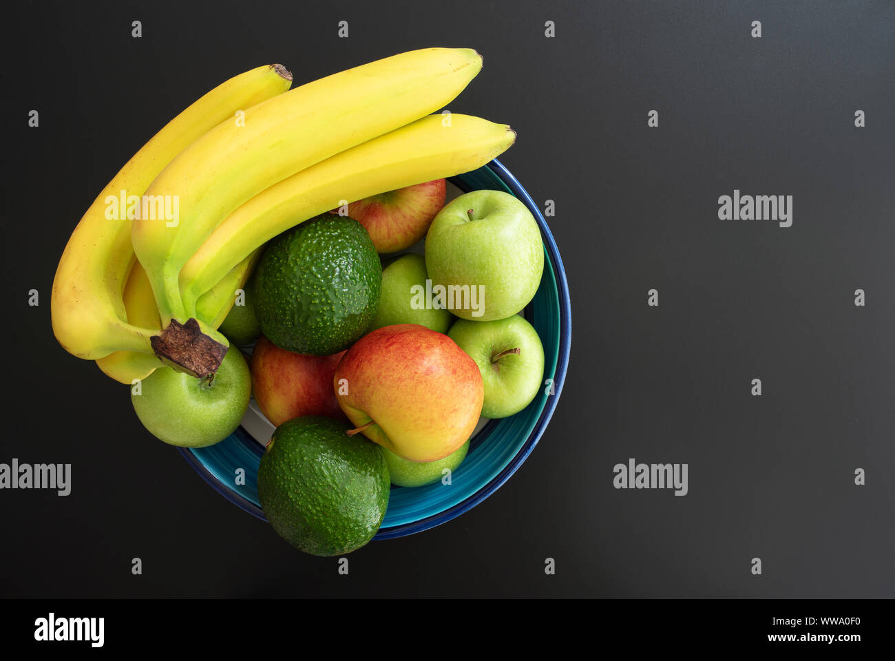 Blick von oben auf die Keramik Schüssel mit gesundem Obst auf dunklem Hintergrund gefüllt Stockfoto
