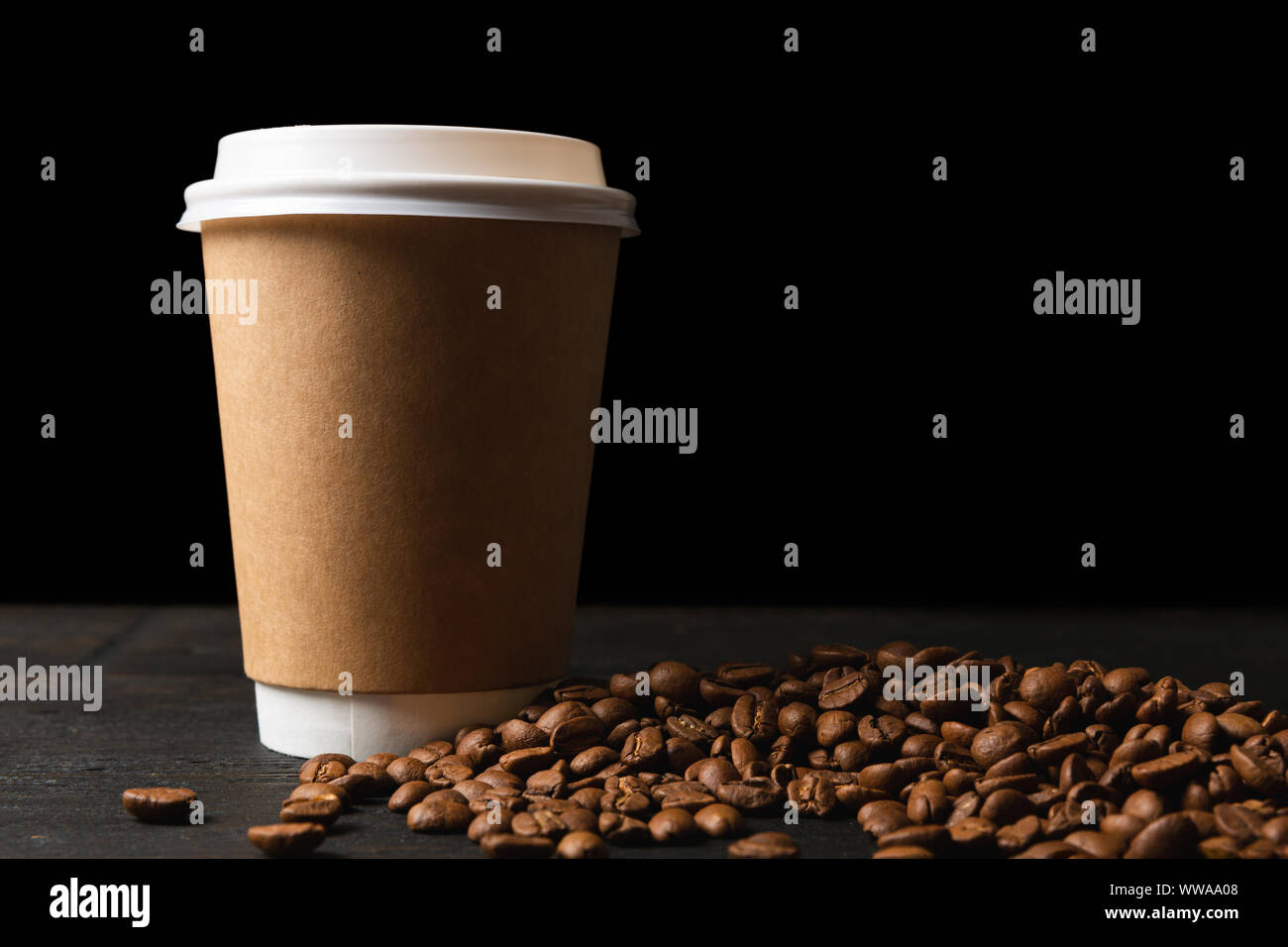 Papier Tasse Kaffee und Kaffeebohnen auf dunklen Holztisch. Gute Qualität Stockfoto
