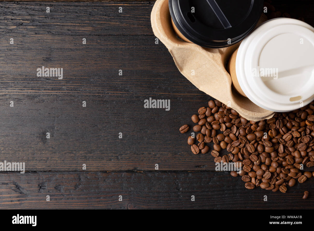 Zwei Tassen Kaffee im Becherhalter und Kaffeebohnen auf dunklen Holztisch. Gute Qualität Stockfoto