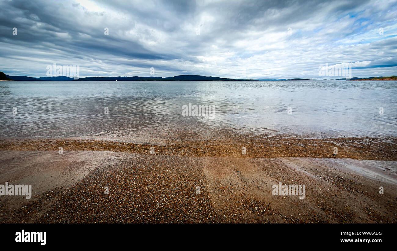 Dramatische Himmel über schönen ruhigen Wasser im Bottnischen Meerbusen. Storsand, Hohe Küste im Norden Schwedens. Stockfoto