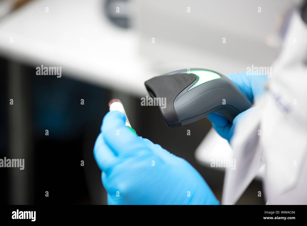 Barcodescanner und Reagenzglas über Monitor von kompletten Blutbild Analyzer im Hintergrund. Stockfoto
