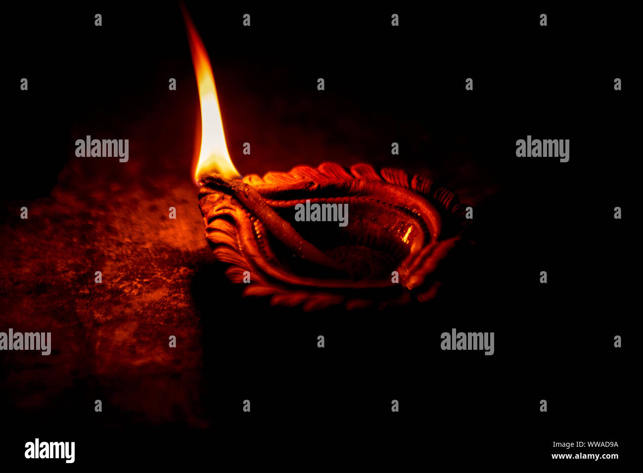 Schließen Sie herauf Bild eines beleuchteten Ton diya oder Lampe auf dem Boden auf Diwali - eine Indische hinduistische Lichterfest auf schwarzem Hintergrund isoliert. Stockfoto