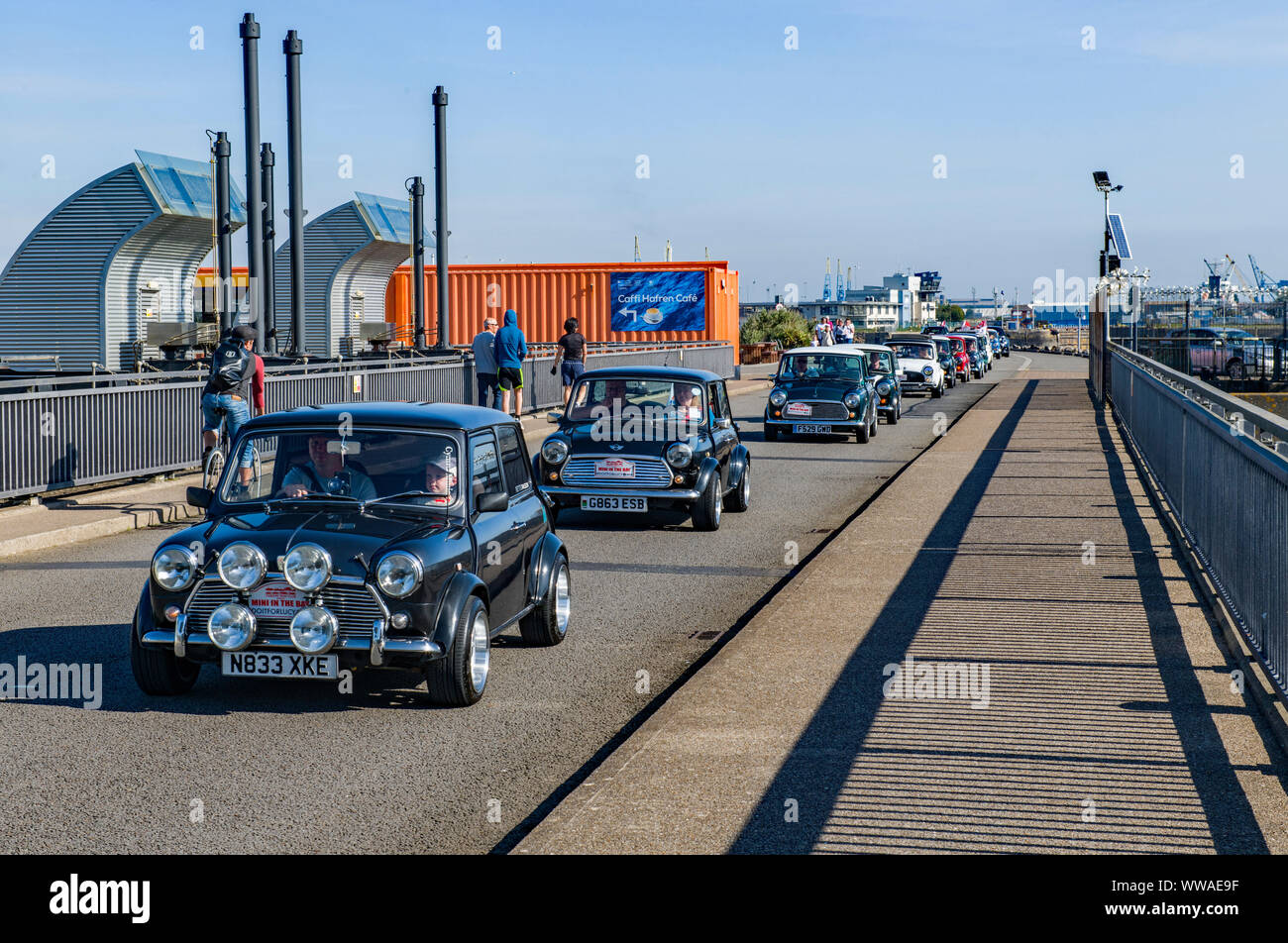 Cardiff Mini Club mit einer Prozession von 100 Minikraftwagen, die an einem sonnigen Sommertag die Cardiff Bay Barrage überqueren. Das war ein Benefiz-Erbauer. Stockfoto