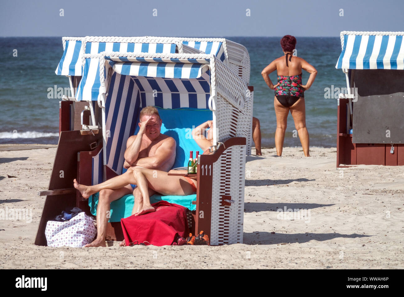 Menschen in einem Strandkorb Stuhl geniessen Sie einen sonnigen Nachmittag am Strand von Warnemünde Deutschland Ostsee Urlaub Stockfoto