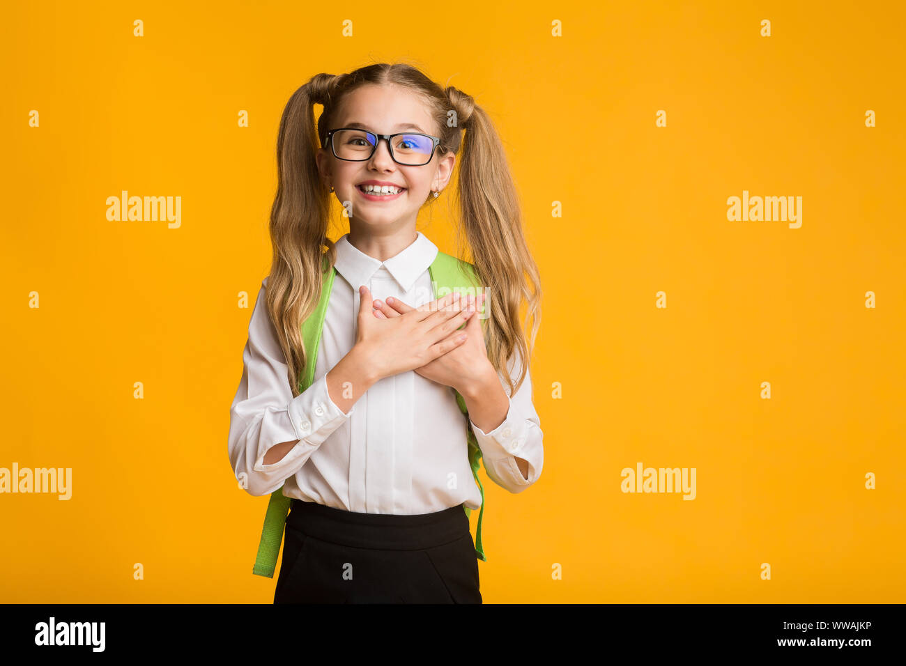 Dankbar Schule Mädchen lächelnd die Hand auf die Brust, Studio shot Stockfoto