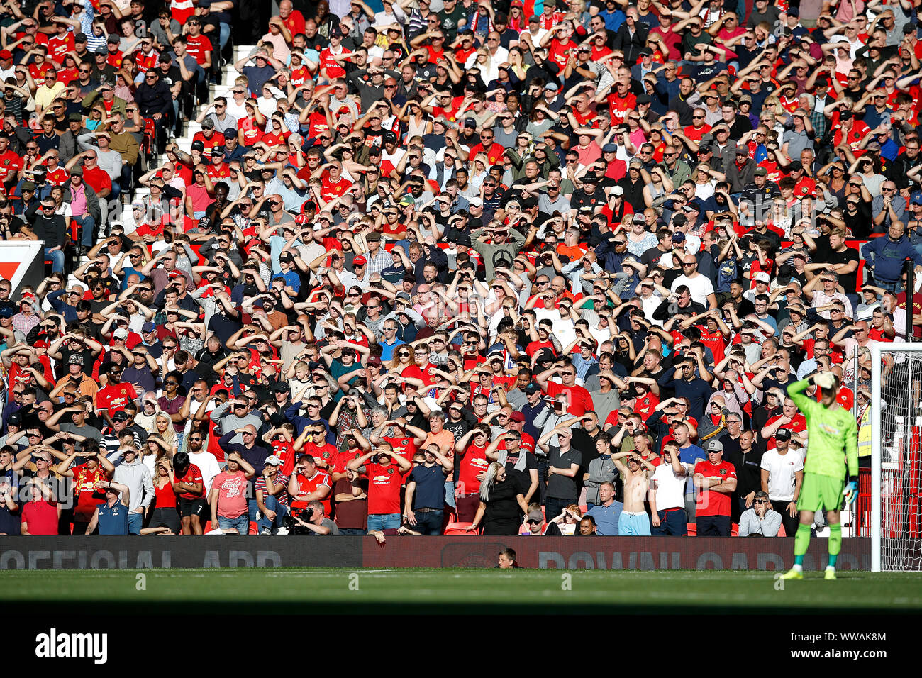 Manchester United Fans schützen Ihre Augen vor der Sonne während der Premier League Spiel im Old Trafford, Manchester. Stockfoto