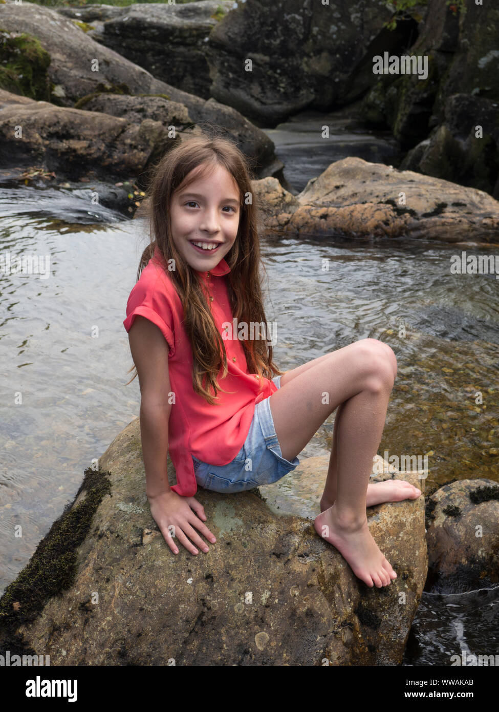 Holiday snap von 9 Jahre altes Mädchen auf einem Felsen in Schottland sitzen Stockfoto