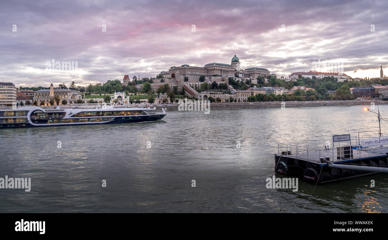 Sonnenuntergang Blick auf die Budaer Burg über der Donau in Budapest, Ungarn mit einem Fluss Kreuzfahrt vorbei an Stockfoto