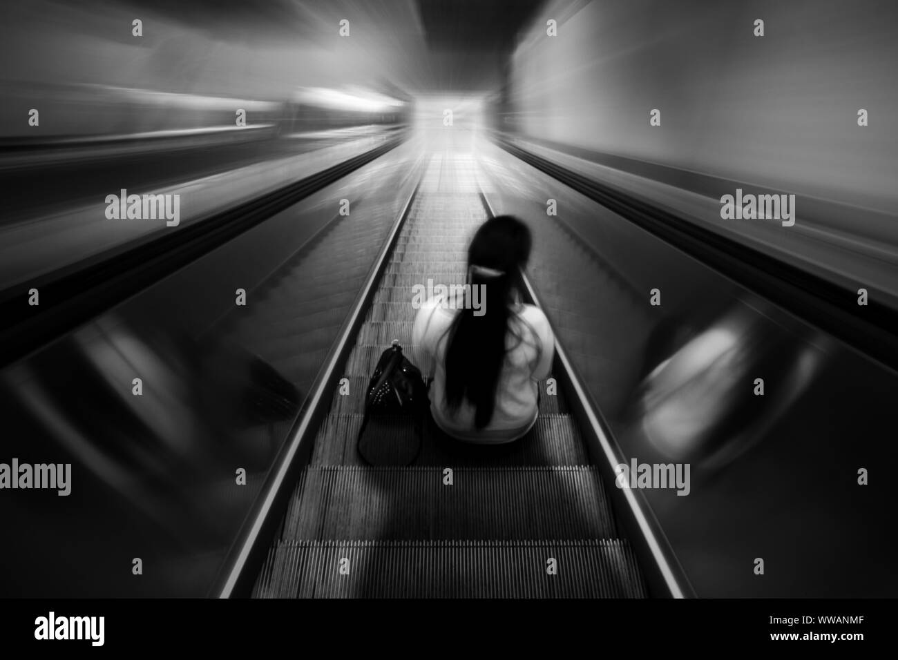 Einsame Frau sitzt auf einer Rolltreppe Stockfoto