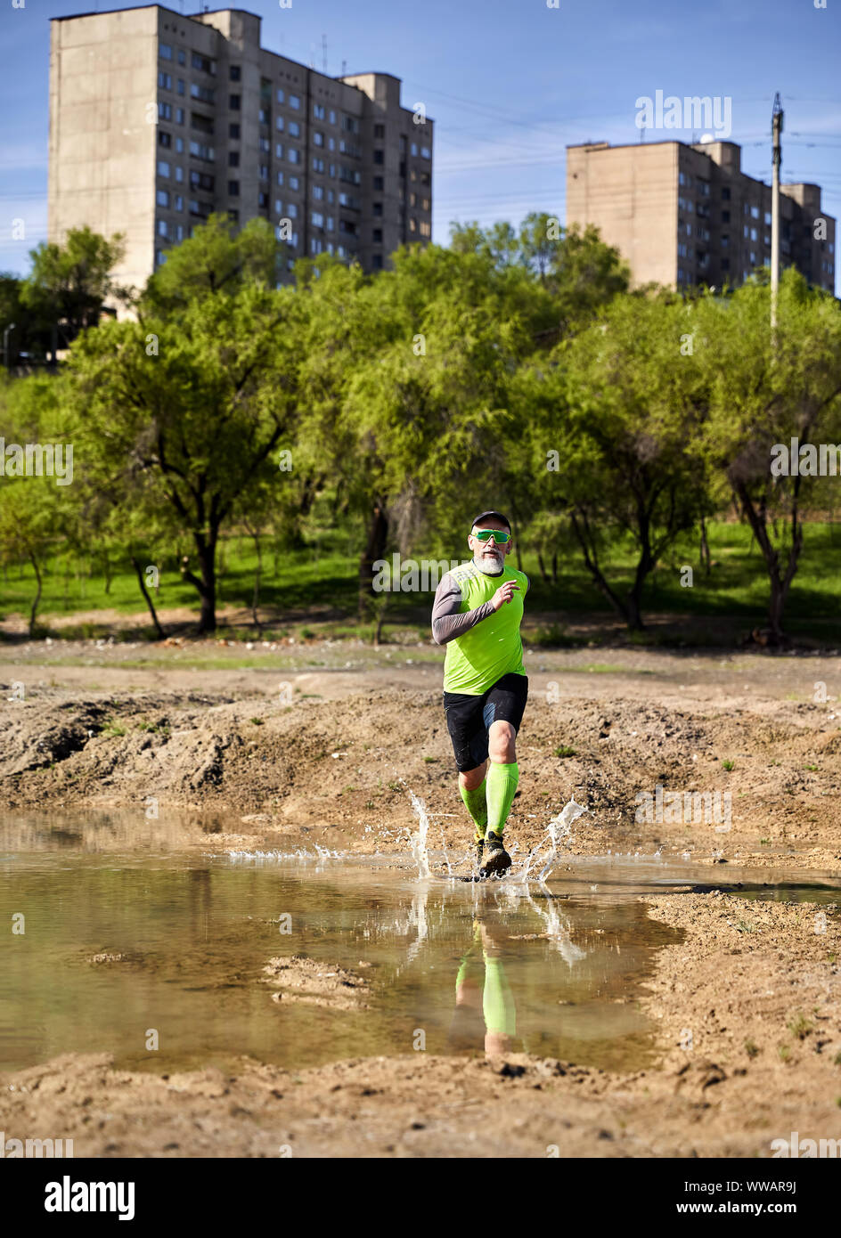 Mann mit dem grauen Bart, der auf die schmutzige Spur mit pool im City Park am Morgen. Gesunder Lebensstil Konzept Stockfoto