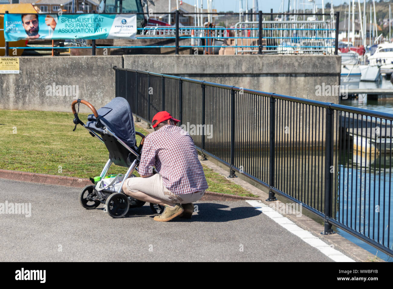 Ein Vater allein mit einem Kind im Kinderwagen am Wasser am Meer suchen Stockfoto
