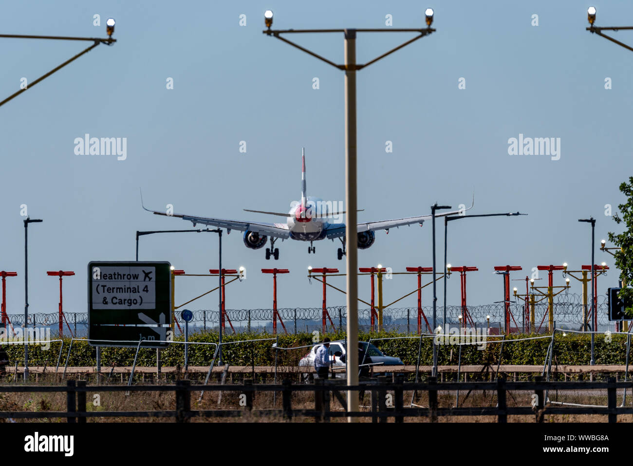 British Airways Jet Airliner Flugzeug Landung am Flughafen London Heathrow in Hounslow, London, Großbritannien, mit Landebahn Ansatz Lichter und Straßenverkehr. Auto, Zeichen Stockfoto