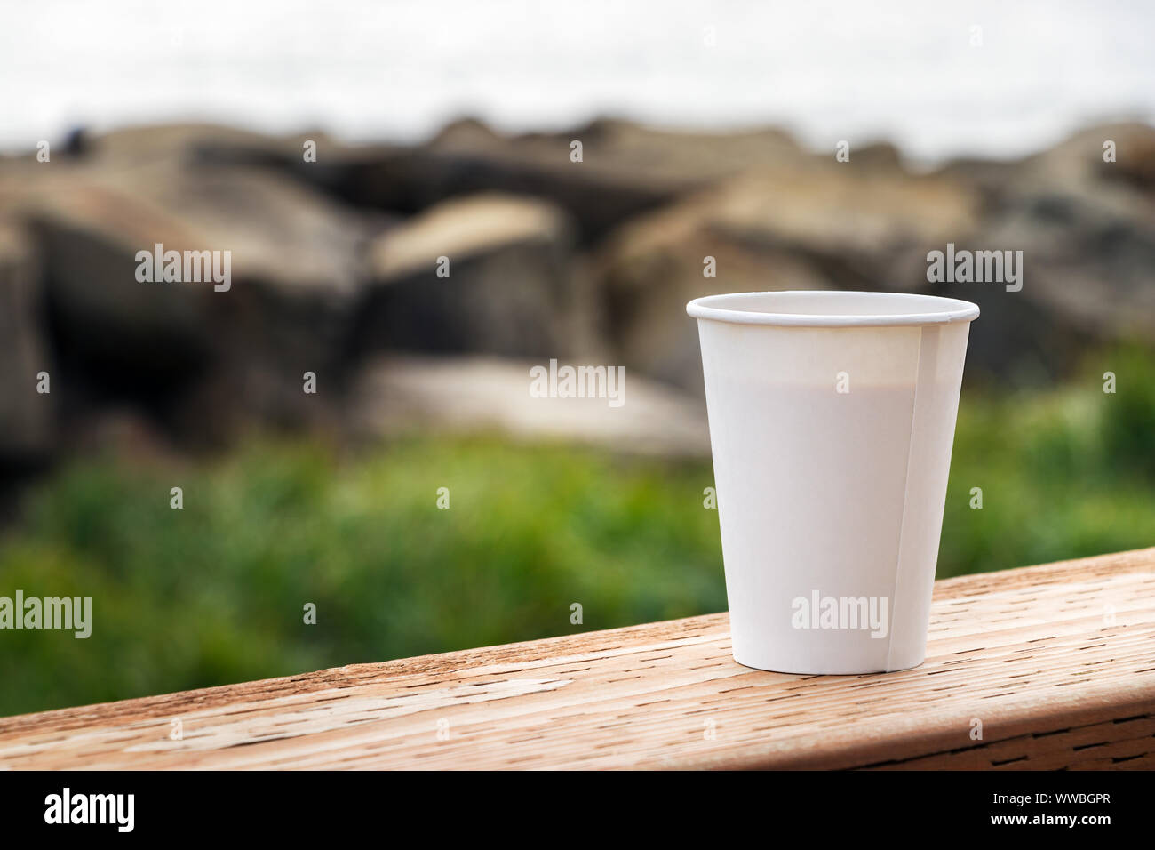 Eine verfügbare Papier Tasse Kaffee placer auf einem hölzernen Tisch über einen Natur Hintergrund, im Freien, Nahaufnahme. Stockfoto