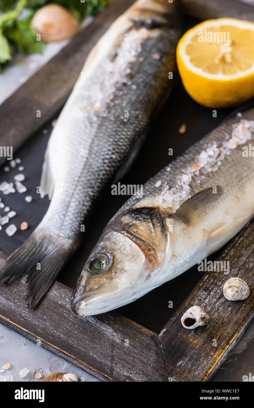 Frischer Seebarsch bereit zu Kochen. Fisch mit Petersilie, Zitrone und rosa Himalaya Salz. Das Konzept der gesunde und richtige Ernährung. Stockfoto