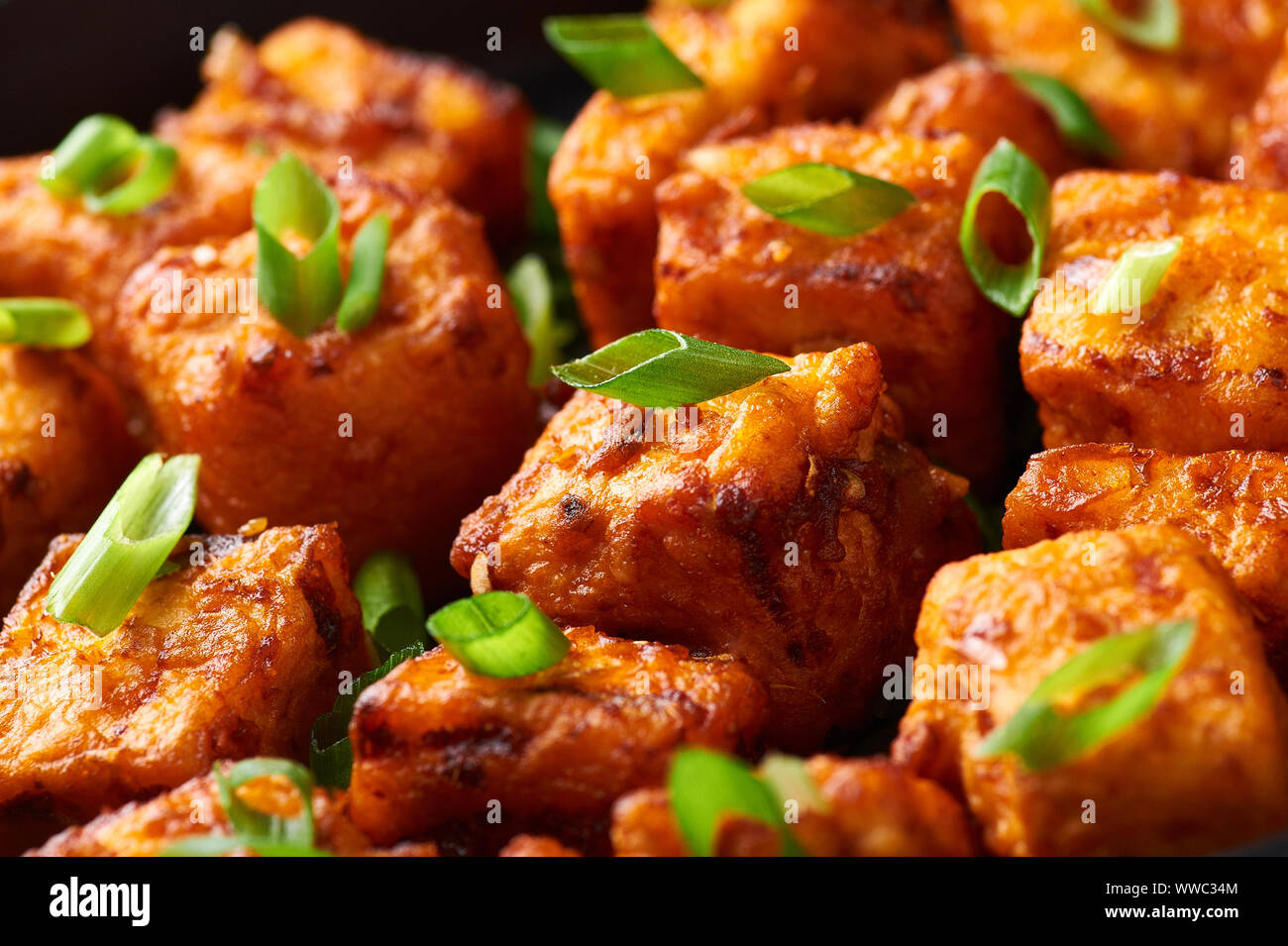 Paneer Mandschurischen oder Paneer 65 in der Schüssel am Schwarzen konkreten Hintergrund. Paneer mandschurischen ist indische, chinesische Küche Teller mit panner Käse, Tomaten, auf Stockfoto