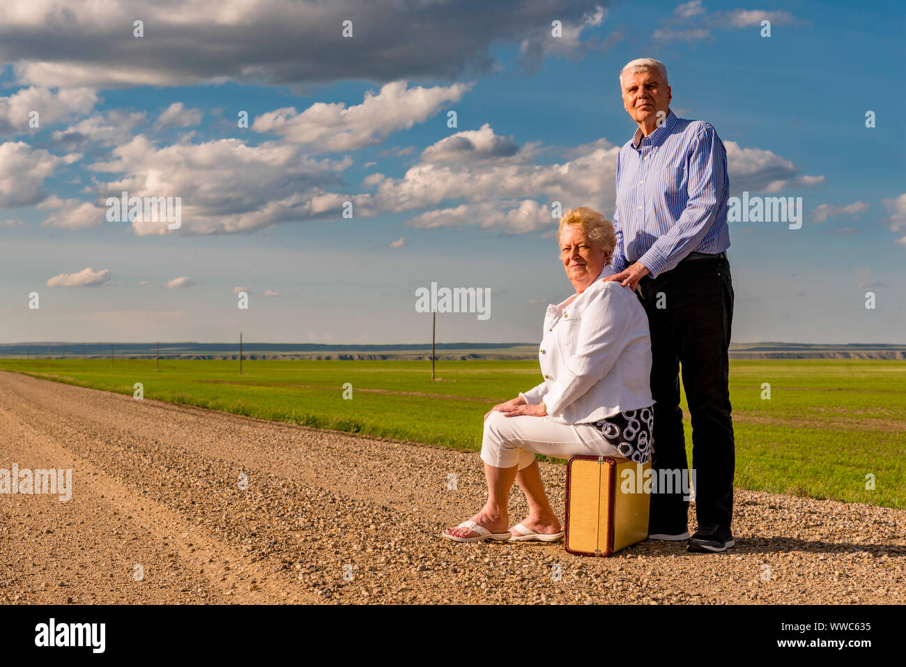 Senior Paar mit Vintage Koffer auf einer Schotterpiste in Saskatchewan, Kanada. Abenteuer Konzept. Mit Blick auf die Zukunft Konzept Stockfoto