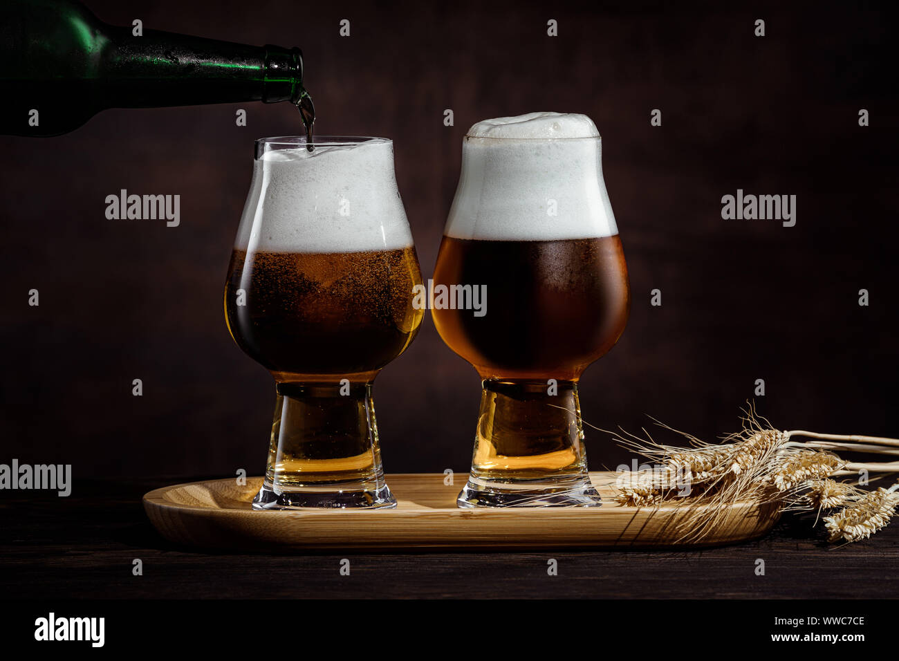 Zwei Gläser kalte dunkle Bier und Weizen ährchen auf dunklem Hintergrund. Stockfoto