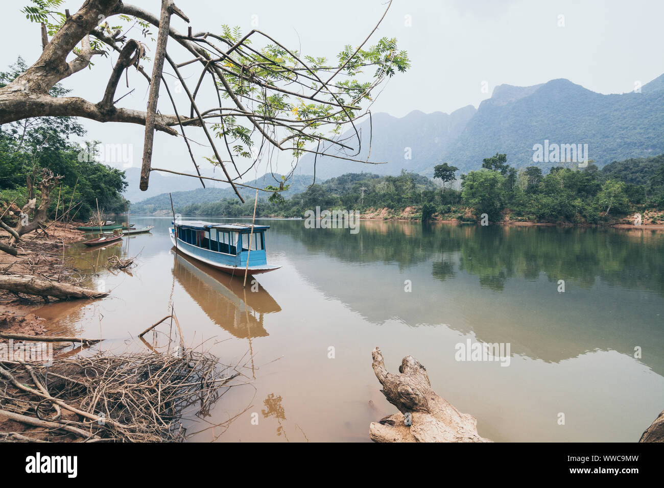 Die traditionellen laotischen Holz- Slow Boat auf Nam Ou Fluss in der Nähe von Nong Khiaw Dorf, Laos. Reflexion im Wasser Stockfoto Die traditionellen laotischen Holz- Slow Boat auf Nam Ou Fluss in der Nähe von Nong Khiaw Dorf, Laos. Reflexion im Wasser Stockfoto
