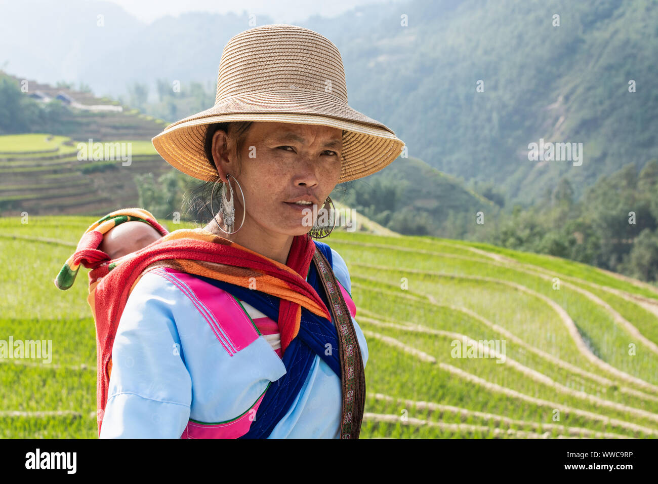 Sapa, Vietnam - Mai 2019: Frau aus der ethnischen Gruppe der Hmong in traditioneller Kleidung Wandern neben dem Reis Terrasse in Lao Cai Provinz Stockfoto