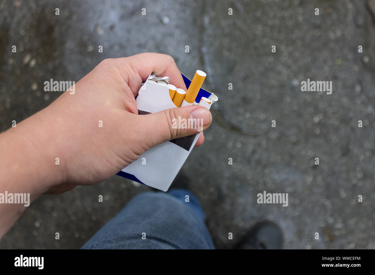 Eine Packung Zigaretten in den Händen eines Rauchers und eine längliche Zigarette Stockfoto