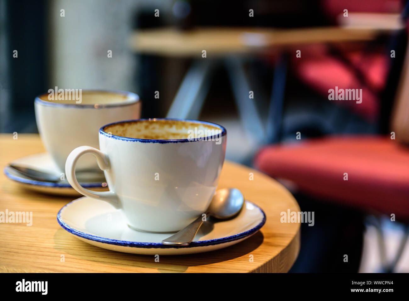 Zwei leere Tassen Kaffee Latte auf Cafe Tabelle. Stühle für den Hintergrund. Elektrische Beleuchtung Stockfoto