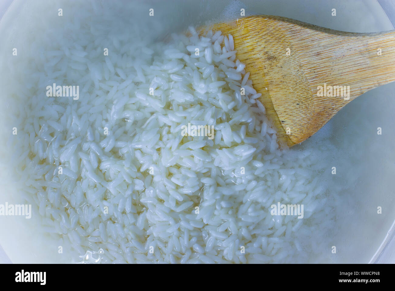Flache Oberseite legen Blick hinunter von eingeweichten Reis, Getreide, trübe Flüssigkeit Wasser in Glasschale, Huhn und wilder Reis Suppe. kochen Hausgemachte frische cremige Suppe Hoch Stockfoto