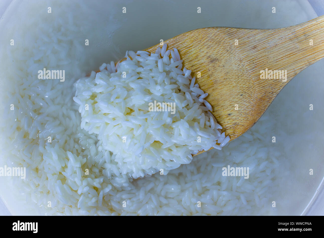Flache Oberseite legen Blick hinunter von eingeweichten Reis, Getreide, trübe Flüssigkeit Wasser in Glasschale, Huhn und wilder Reis Suppe. kochen Hausgemachte frische cremige Suppe Hoch Stockfoto