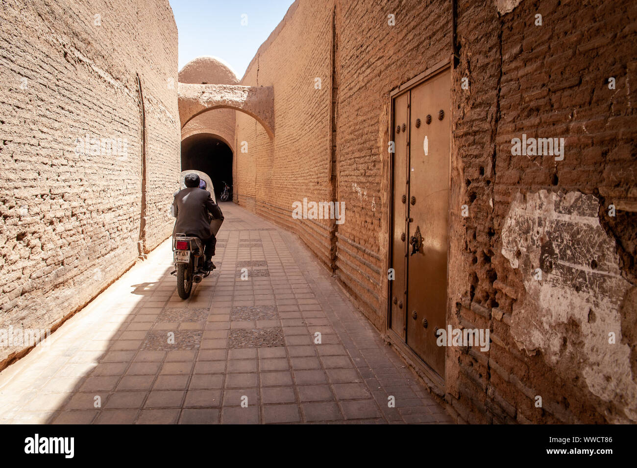 Ein Mann sein Motorrad in einer kleinen Straße in Shiraz, Iran fahren Stockfoto