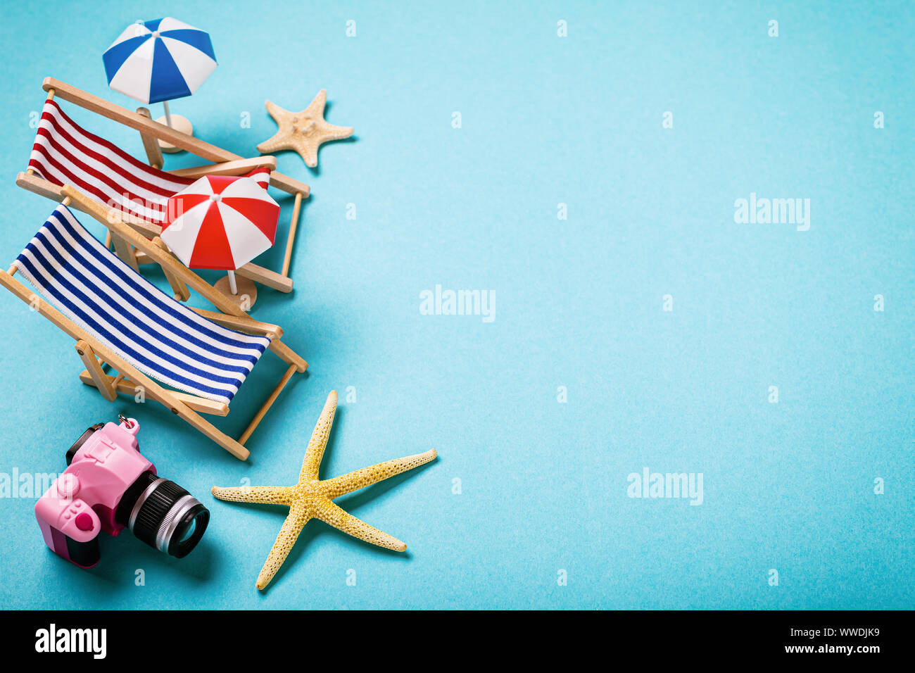 Strand von Elementen auf einem blauen Hintergrund. Liegestühle, Muscheln und eine Kamera mit Platz kopieren Stockfoto