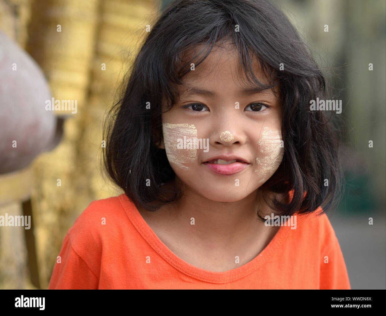 Süße kleine Burmesische Mädchen mit Patches von gelblich-weißes, traditionelles thanaka Gesicht Kosmetik auf ihren Wangen und Nase Lächeln für die Kamera. Stockfoto