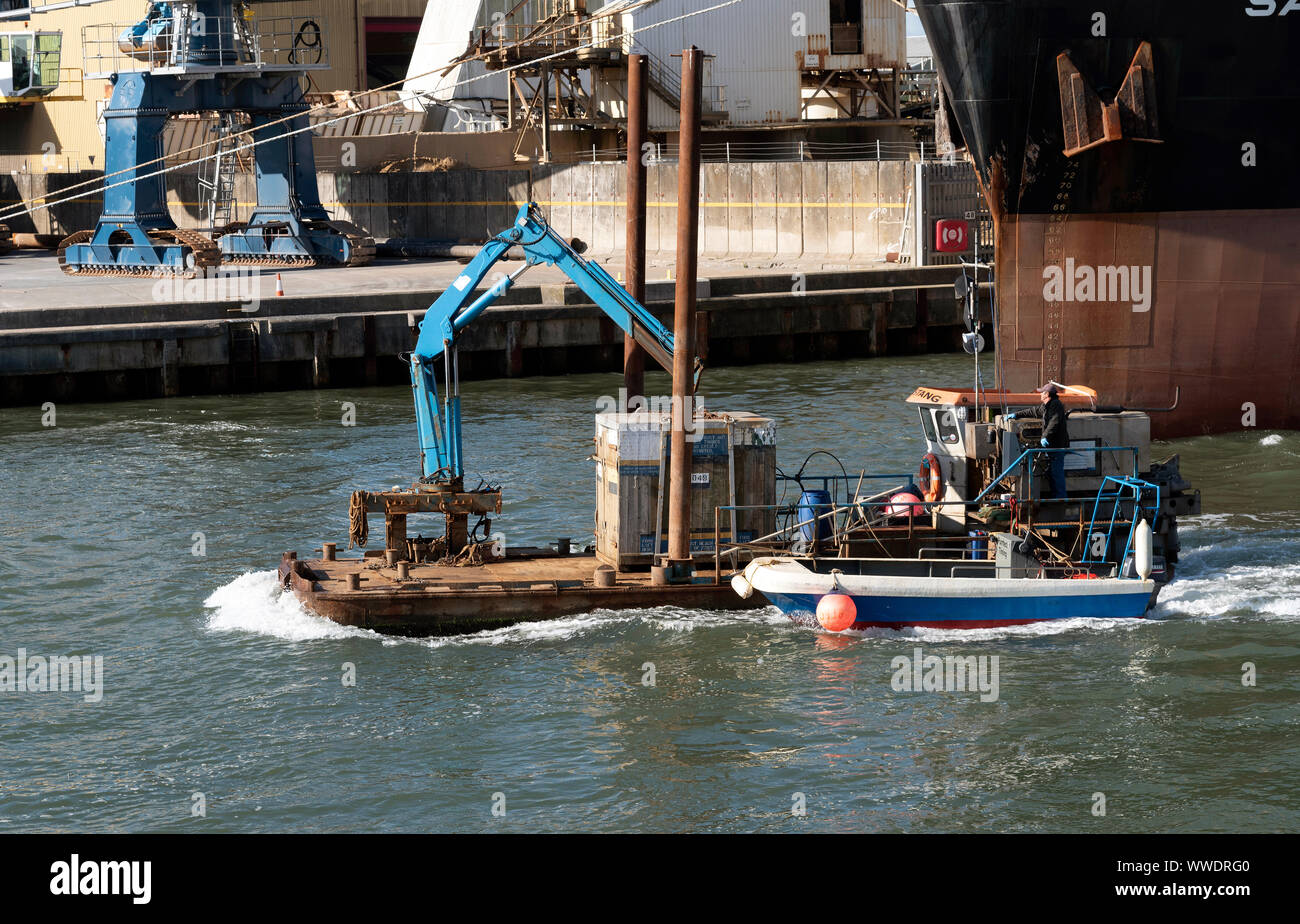 Hafen von Poole, Südengland, Großbritannien. Ein deck Frachtschiff unterwegs und arbeiten in den Hafen von Poole, Großbritannien. Vorbei an den Sand Heron ein größeres Schiff. Stockfoto