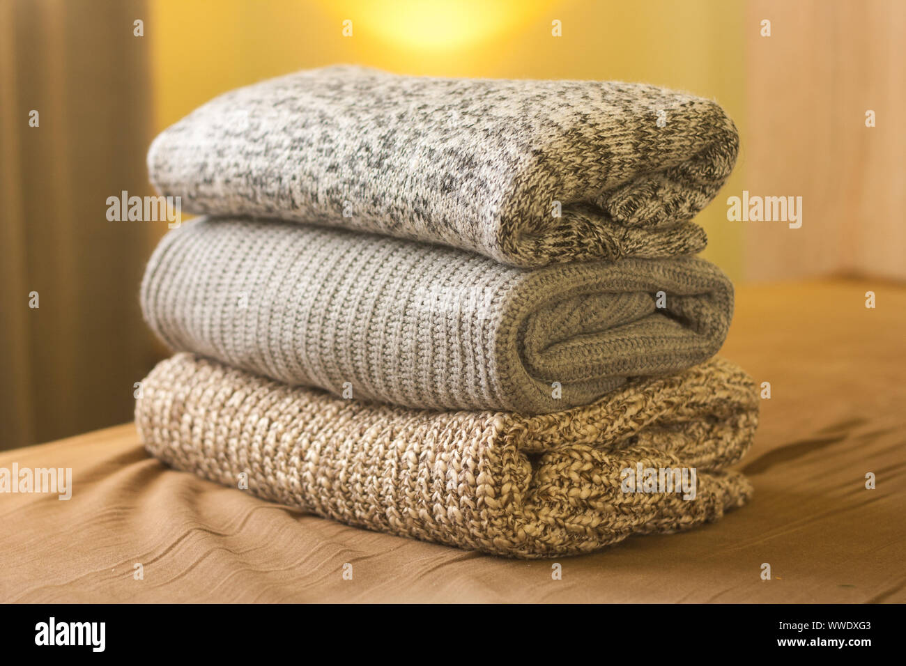Ein Stapel aus Gewirken Winter oder Herbst Pullover auf dem Holz Bett. Warme, bequeme Kleidung. Stockfoto