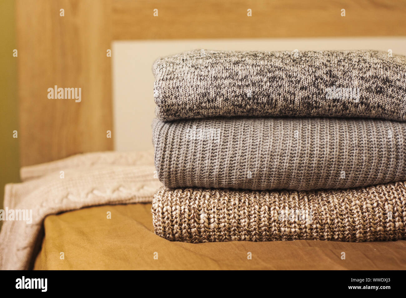 Ein Stapel aus Gewirken Winter oder Herbst Pullover auf dem Holz Bett. Warme, bequeme Kleidung. Stockfoto