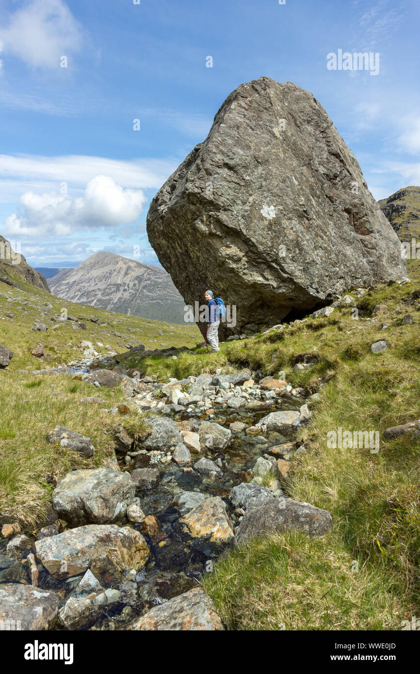 Weiblichen Hügel-Walker stehen unter riesigen Felsblock, Fionna Choire, Blaven, Isle Of Skye, Schottland, UK Stockfoto