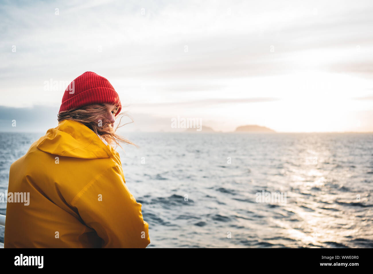 Anone mann Reisender schwimmende Schiff suchen bei Sonnenuntergang Meer nach Sturm und nebligen Bergen auf der Skyline. Lifestyle travel Outdoor skandinavischen verbindlich Stockfoto