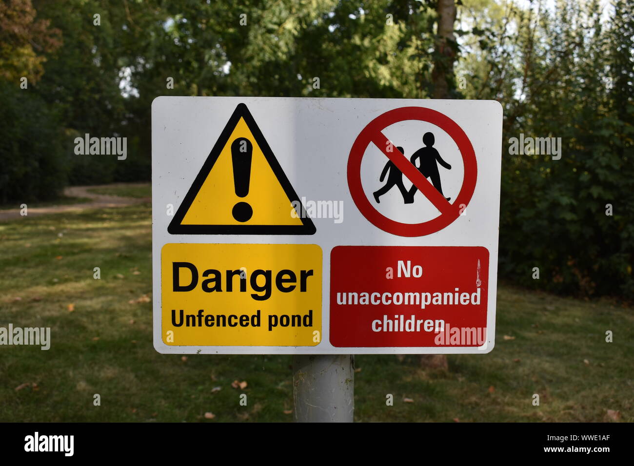Dies ist ein Warnschild: "Gefahr nicht eingezäunten Teich' und 'Keine unbegleiteten Kinder'. Stockfoto