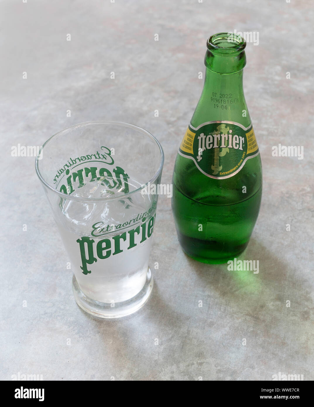 Eine Flasche Perrier Wasser und Perrier Glas mit Eis und Wasser. Stockfoto