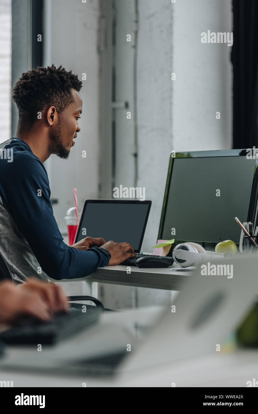 Junge afrikanische amerikanische Programmierer im Büro in der Nähe von Kollegen arbeiten Stockfoto