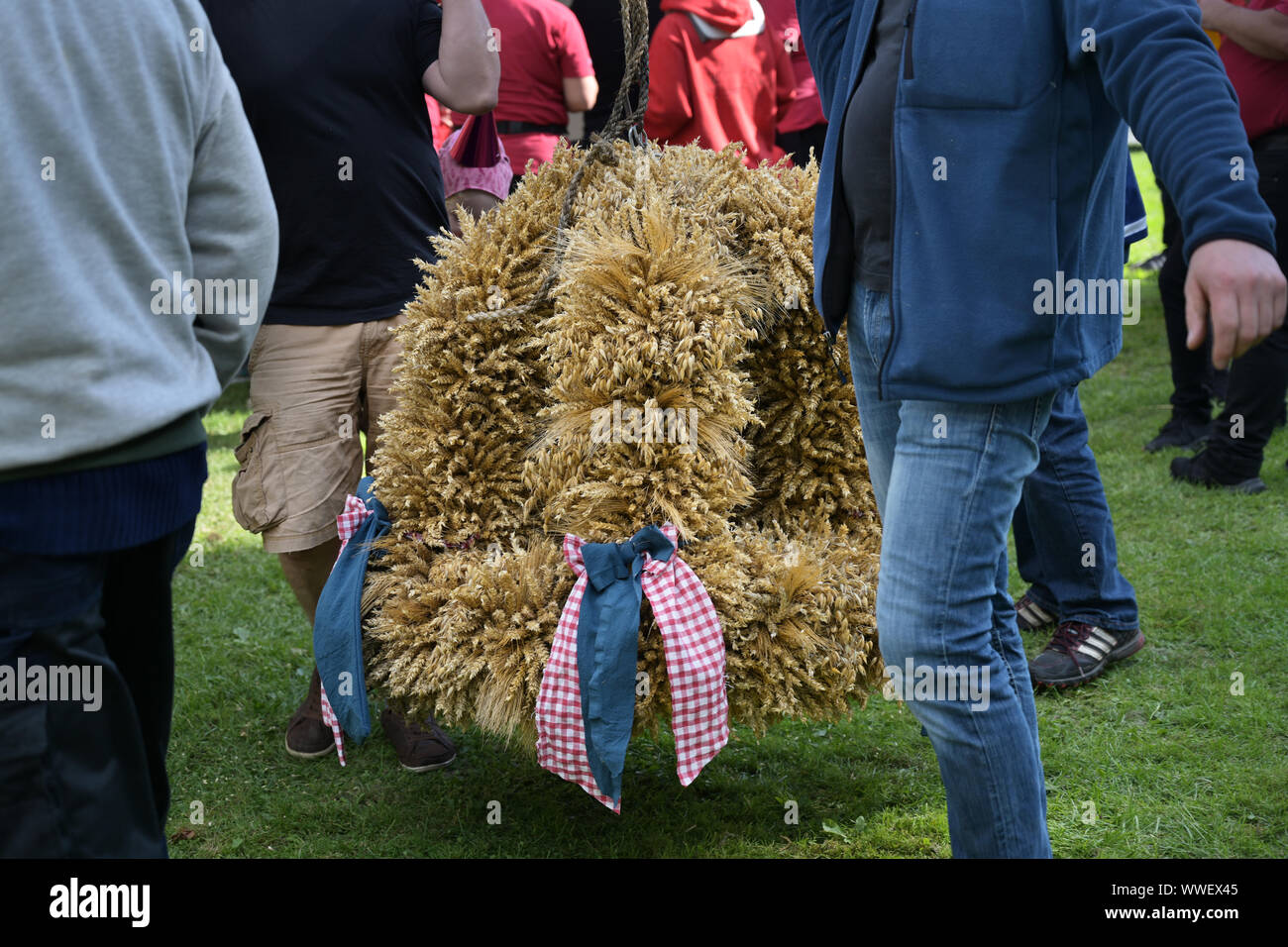 Starke Männer tragen die traditionelle Ernte Krone aus Getreide halme auf den festlichen Bereich für Thanksgiving, ausgewählte konzentrieren Stockfoto