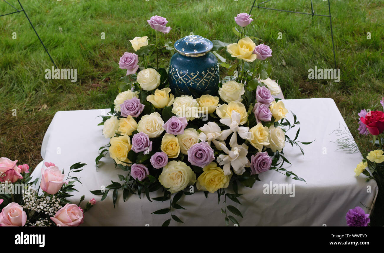 Bestattungskonzept und Trauerkonzept - Blumen rund um Urne Stockfoto