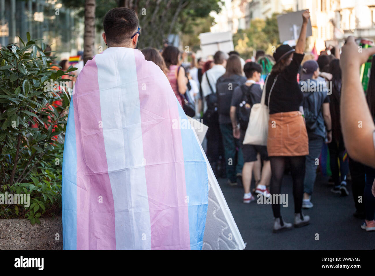 Mann, eingewickelt in eine transsexuelle Flagge von hinten während einer Gay Pride gesehen. Dieses Flag ist eines der Symbole der LGBTQ und Transgender und Gemeinschaft Stockfoto