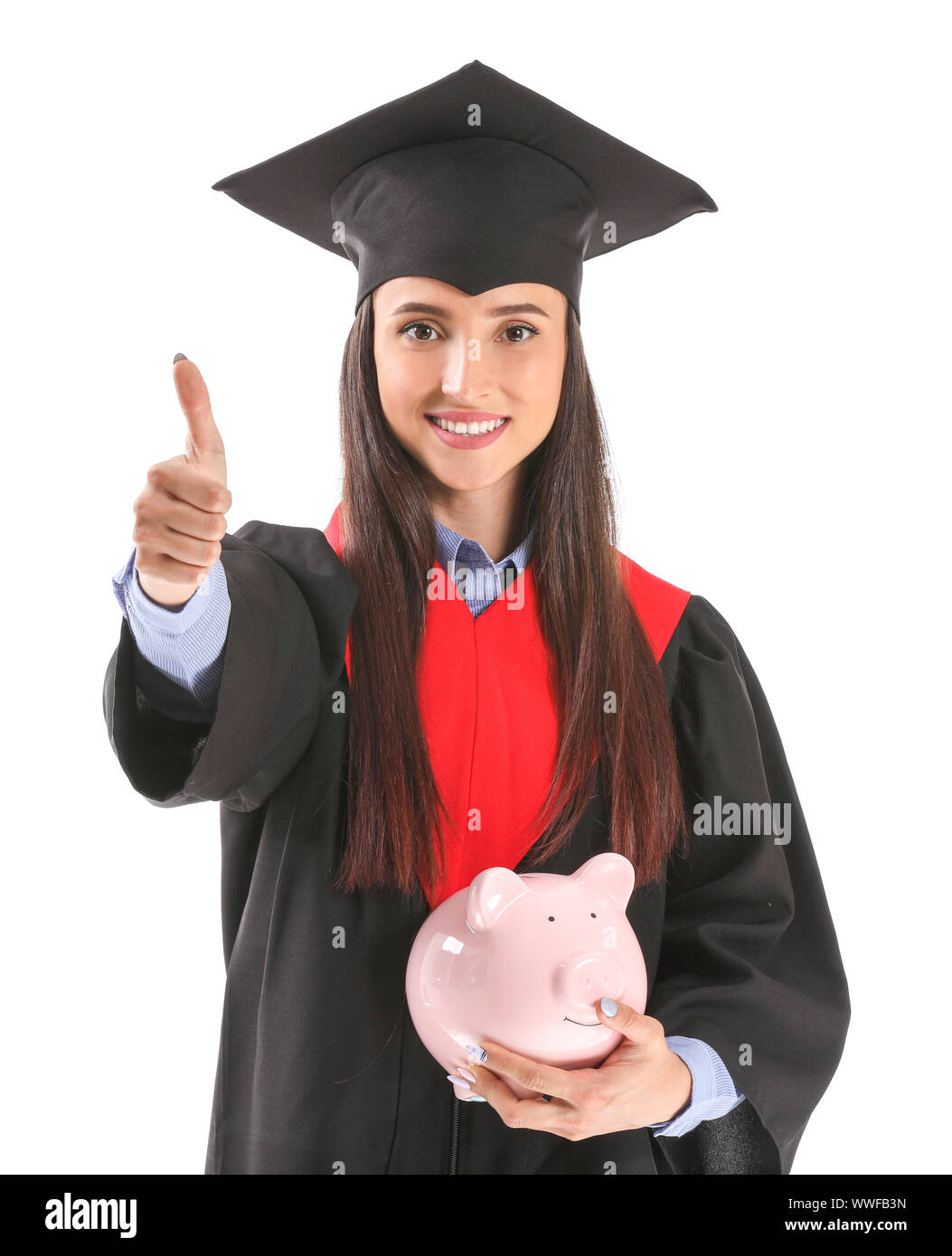 Weibliche Absolventin mit Sparschwein mit Daumen - bis auf weißem Hintergrund. Studiengebühren Konzept Stockfoto